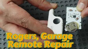Rogers garage door remote control with detached battery holder bracket and damaged PCB traces undergoing advanced microsoldering repair at AppleFix & Tech Engineers Hamilton New Zealand. The image shows the remote control disassembled with the circuit board exposed after battery terminal damage caused lifted solder pads and broken positive power traces requiring precision PCB trace reconstruction, circuit board repair, and component-level electronics repair by professional microsoldering technicians.