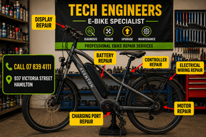 **Alt text:** Professional eBike repair workshop in Hamilton NZ showing an electric bike with labels for battery, motor, controller, display, charging port and electrical wiring repairs at Tech Engineers.